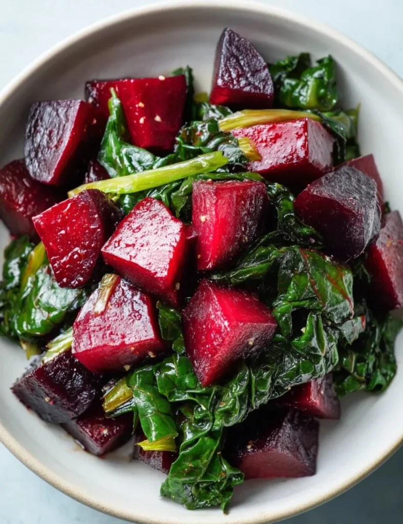 Vibrant roasted beets served with tender sautéed beet greens on a plate.
