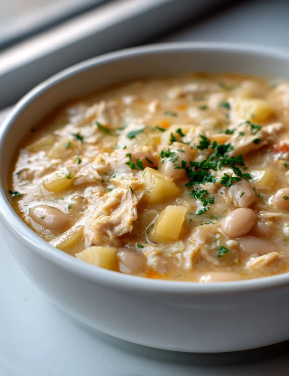 Delicious White Cheddar Apple Chicken Chili in a bowl, garnished with fresh herbs
