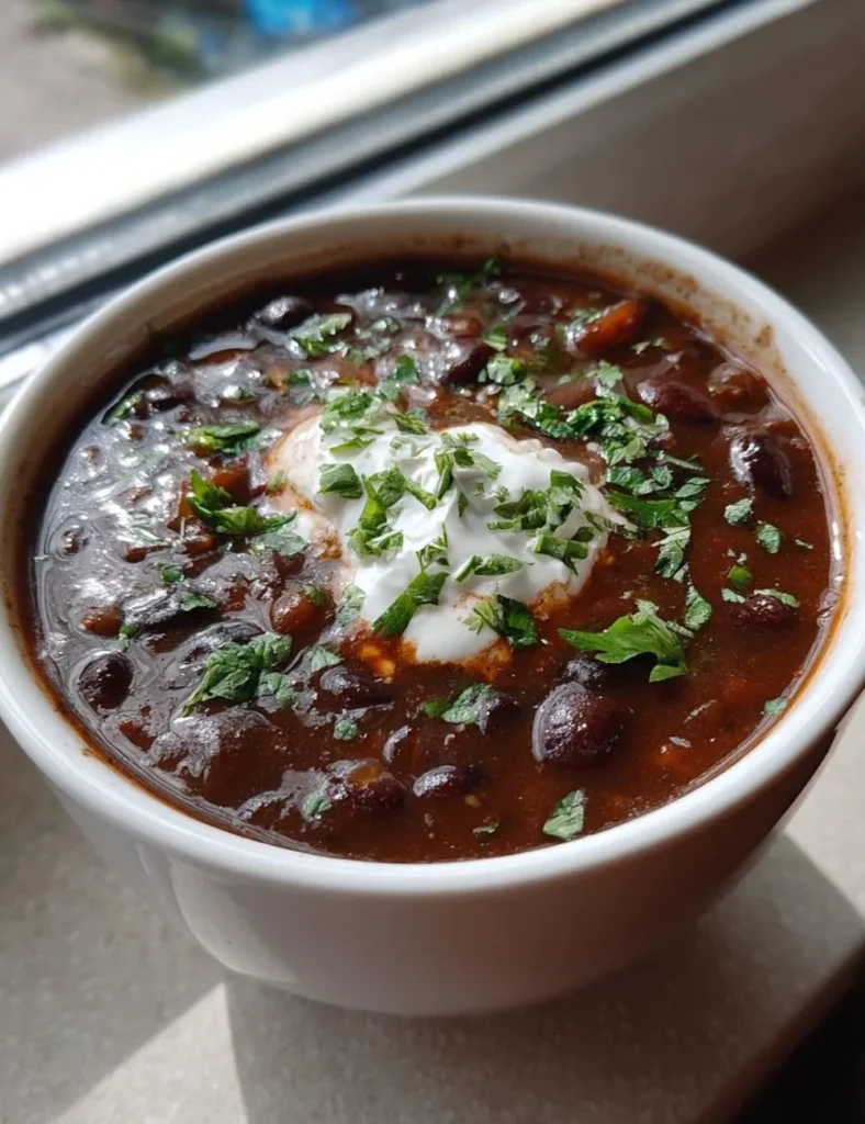 Bowl of easy black bean soup garnished with cilantro and lime.