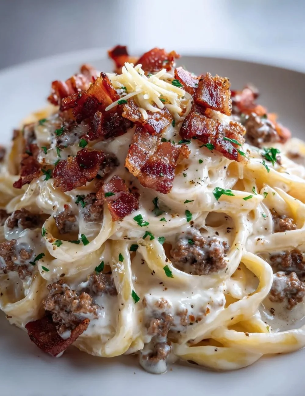 Loaded beef bacon cheeseburger alfredo pasta topped with cheese and crispy bacon