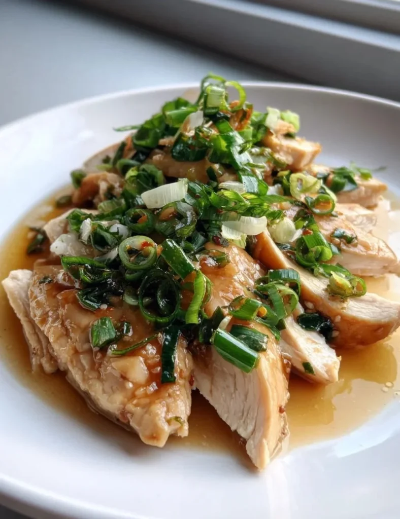 Plate of scallion chicken garnished with fresh scallions and served with rice.