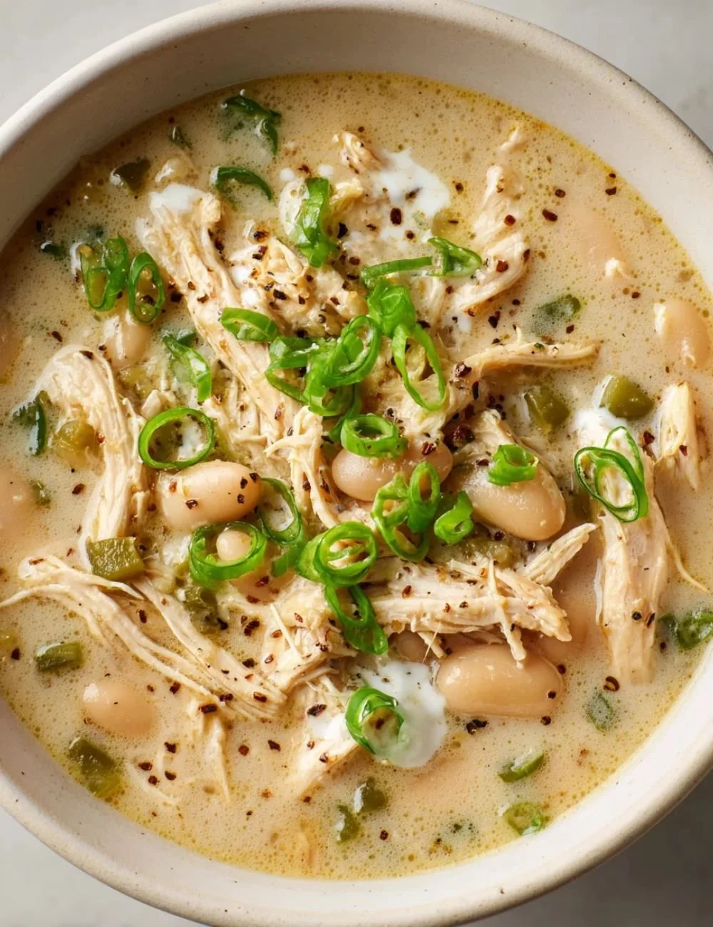 Bowl of creamy white chicken chili topped with cilantro and jalapeños.