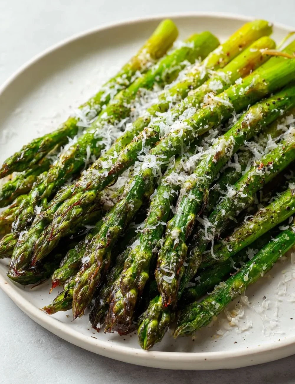 Plate of classic baked asparagus topped with parmesan cheese