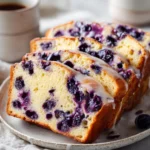 Sliced blueberry sourdough bread with lemon glaze on a wooden cutting board
