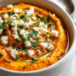 Creamy whipped roasted carrot feta dip served in a bowl with fresh herbs