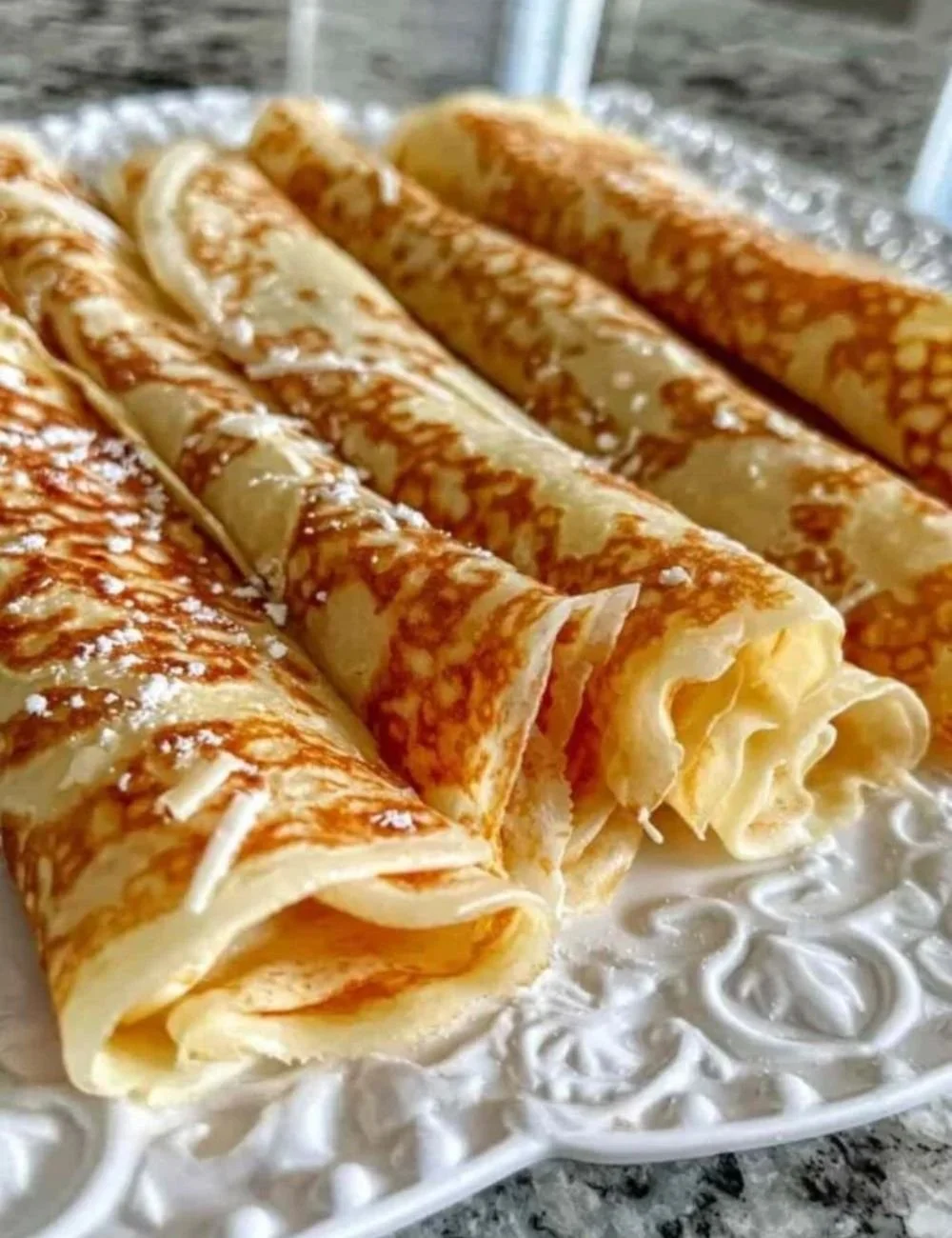 High protein oatmeal crepes stacked on a plate with fruit garnish