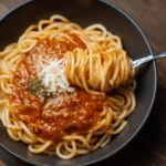 Creamy macaroni dish topped with cheese and herbs, served in a bowl.