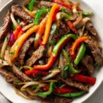 Sheet pan steak fajitas with colorful bell peppers and onions ready to serve.