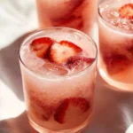 Refreshing Strawberry Coconut Cooler drink in a glass with strawberries and coconut.