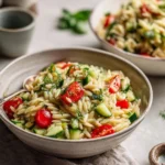 Delicious spring orzo salad with colorful vegetables in a bowl